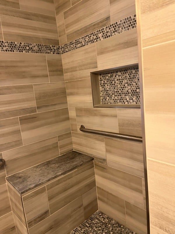 Renovated walk-in shower with wood-look tile and grab bar