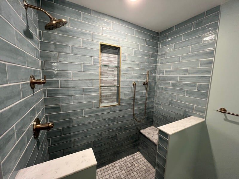 Gray tile shower with bench and mosaic floor